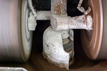 millstones of industrial melanger grind cocoa in the process of making chocolate, blurry in motion