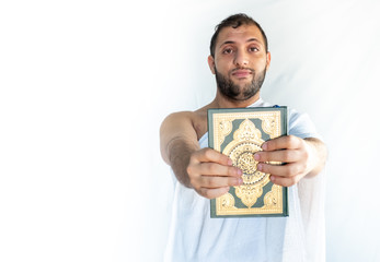 Muslim man wearing alhaj clothes and holding quraan