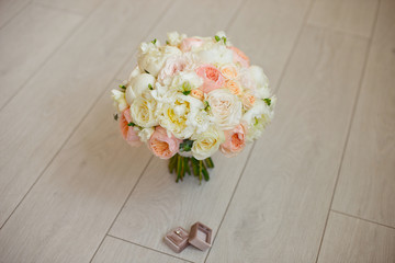Wedding bouquet lying on grey carpet during preparation before celebration. Side view of decorative rose,peonies flowers and leaves bouquet.
