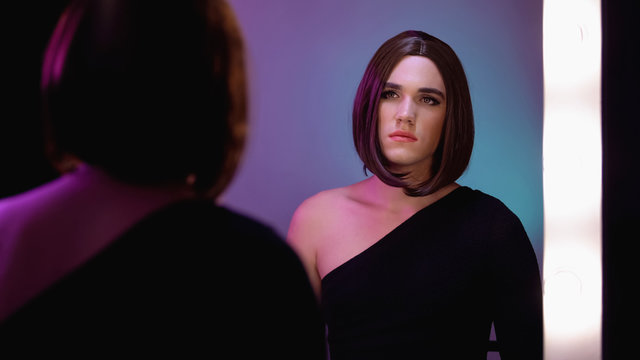 Sad travesty diva looking in mirror, thinking about surgery, gender dysphoria