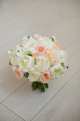 Wedding bouquet lying on grey carpet during preparation before celebration. Side view of decorative rose,peonies flowers and leaves bouquet.