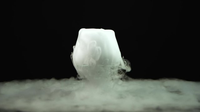 Cognac glass with the effect of dry ice at black background