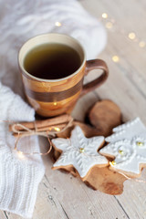 Fototapeta na wymiar Christmas tea time. Mug of hot beverage, gingerbread cookies at wooden and knitted background. Cozy morning breakfast with homemade sweets and cup. Winter food, drinks, new year lights.