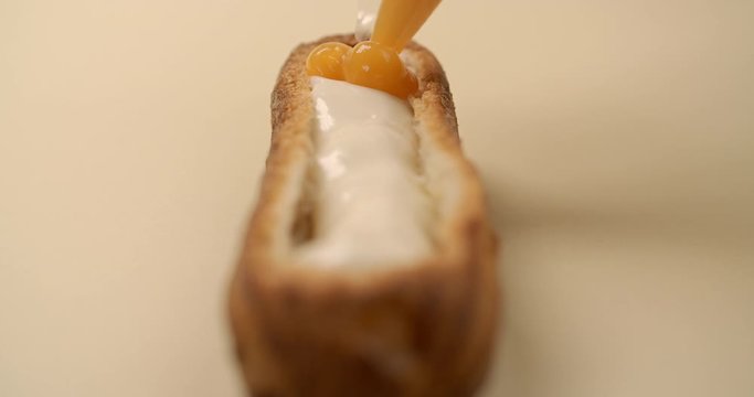 Confectioner is stuffing the eclair with fruit jam and cream, making the sweet dessert in cafe, choux pastry, 4k DCI 120fps Prores 422 HQ 10 bit