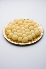 Indian Rasgulla or dry Rosogulla dessert/sweet served in a golden plate. selective focus