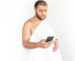 Muslim man making a phone call while wearing pilgrimage clothes