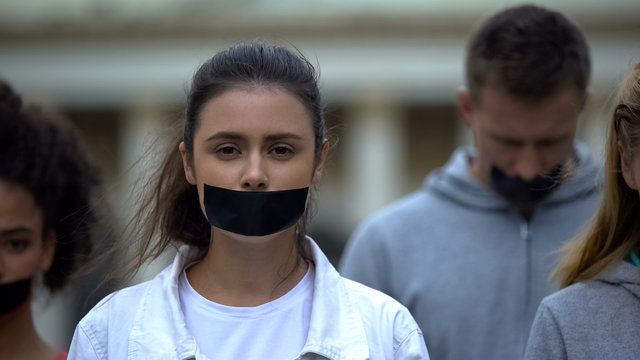Harassment victims with taped mouth looking at camera, call to action concept