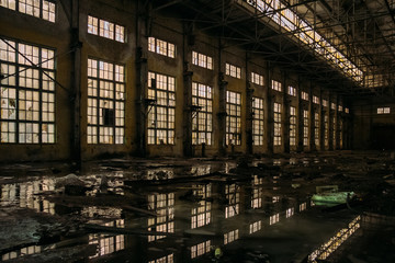Dark dirty flooded dirty abandoned ruined industrial building with water reflections at night