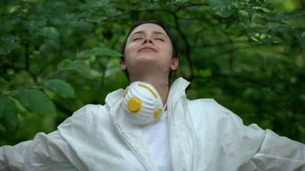 Female breathing free in green forest, took off protective uniform, air quality