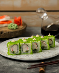 close up of sushi set with crab sticks, cucumber, covered in green tobiko