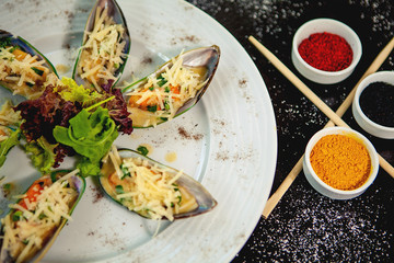 cooked mussel plate garnished with grated cheese and lettuce