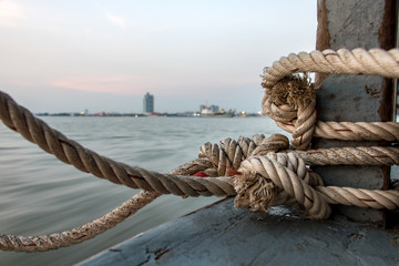 Boat rope tied to a wooden post on a floating boat railing..