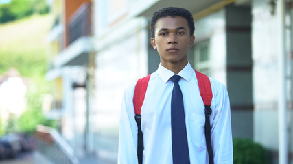 Obraz premium Displeased mixed-race male student with backpack looking into camera, education