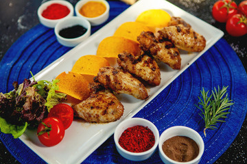 top view of grilled chicken wings served with fried potatoes and fresh salad