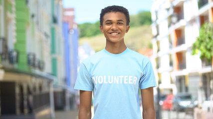 Joyful Afro-American male volunteer smiling at camera outdoors, charity concept