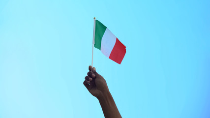 Person holding flag of Italy on sky background, patriotism, liberty, close-up
