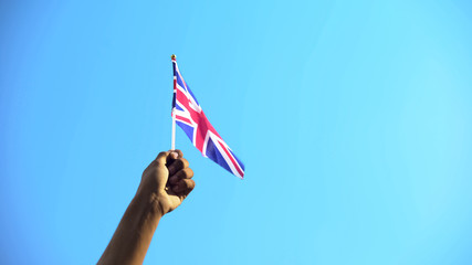 Person holding flag of United Kingdom on sky background, patriotism, close-up