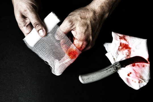 Man is putting the bandage on the wound. Bleeding injury. Deep cut with a knife.