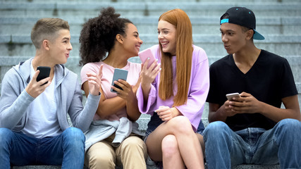 Happy teen female showing friends smartphone message, good news sale application