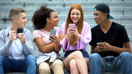 Cheerful red-haired student reading good news on smartphone, online lottery