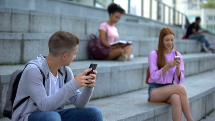 Caucasian millennial with smartphone looking with interest at pretty teenager