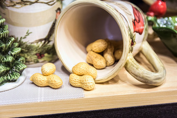 Peanuts lie in a porcelain mug on the table.