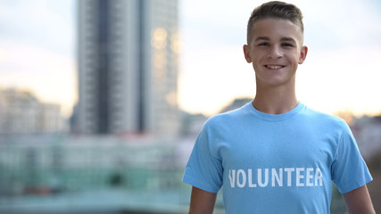 Happy high school pupil in volunteer t-shirt smiling camera, humanitarian aid