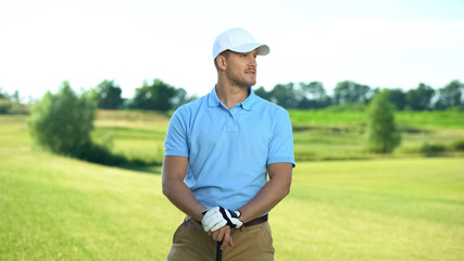 Cheerful golfer holding club and looking to side, ready to sport competition