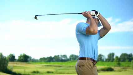 Male golfer hitting ball performing draw position, professional sport, hobby