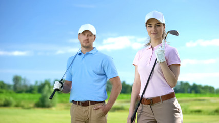 Beautiful female with golf club and sport coach smiling on camera, free lessons