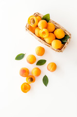 Fresh raw apricots in basket on white background top view copy space, pattern with leaves