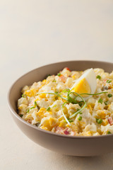 A light egg salad with celery, gherkin, pepper and mayonnaise. Served in a bowl on a light background. Front view.