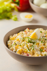 A light egg salad with celery, gherkin, pepper and mayonnaise. Served in a bowl on a light background. Front view.