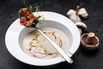Mushroom cream soup in a white plate on a black background