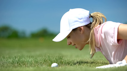 Female golf player looking at ball rolling in hole, hope for success shot, sport