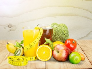 Glasses of fresh juice and fruits with vegetables and measuring tape