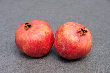 Zwei Granatapfel auf grauem Steingrund