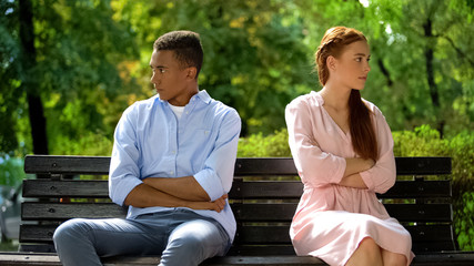 Two offended teenagers sitting on bench separately, quarrel, risk of break-up