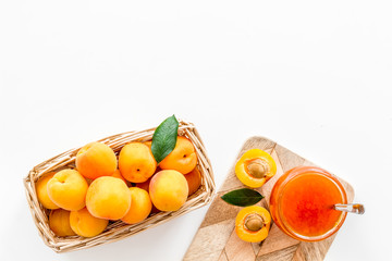Summer preserves. Apricot jam in jar near fresh fruits on white background top view frame copy space