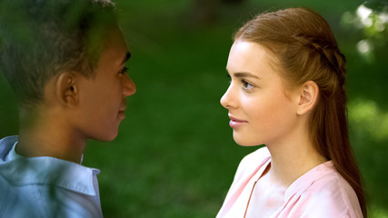 Obraz premium Multi-ethnic teenage couple looking at each other in park, trustful relations