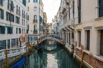Obraz premium Łodzie na wąskim kanale pomiędzy kolorowymi, zabytkowymi domami w Wenecji.