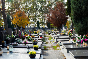 Christian graveyard in autumn. Tombstones decorated with flowers and grave candles. All Saints Day.
