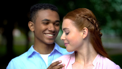 Fototapeta premium Beautiful mixed-race couple hugging looking at each other, tenderness and love