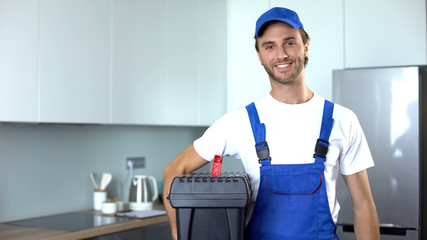 Handyman holding tools standing in kitchen, professional plumbing services