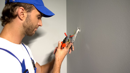 Handyman stripping wires, removing insulation with pliers, electrical services
