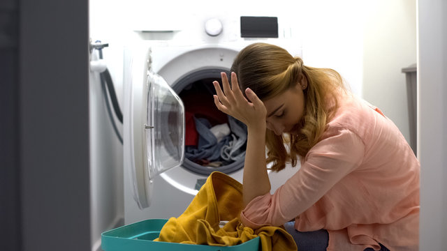 Tired Woman Loading Clothes In Washing Machine, Annoyed With Housework Routine