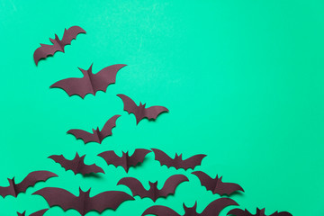 Halloween paper vampire bat decorations on a green background.