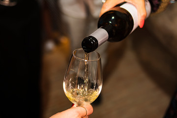 Person serving a glass of wine in glass cup in a dark cellar