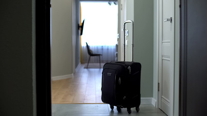Door opened to room with suitcase in middle, check into hotel or check-out