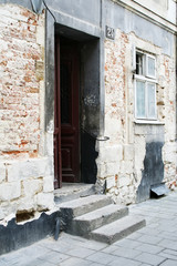 A staircase and an open door leading to an old brick house. There is a window next to the door